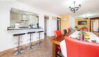 Offene Küche mit Theke und Barhockern, langer Esstisch mit roten Lederstühlen in Finca Palma de Mallorca