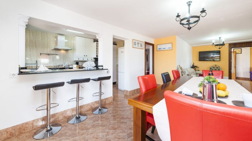 Offene Küche mit Theke und Barhockern, langer Esstisch mit roten Lederstühlen in Finca Palma de Mallorca