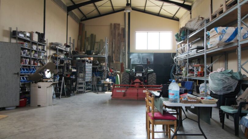 Geräumige Werkstatthalle der Finca mit Traktor, Werkzeugregalen und Garagentor in Son Liebre