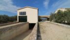Neubau-Finca Son Liebre: Modernes Nebengebäude mit Garage, Natursteinmauern und Zufahrt zur Hauptfinca.