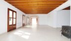 Geräumiges Wohnzimmer der Neubau-Finca mit Holzbalkendecke, Steinbogen und Kaminofen in Son Liebre