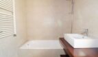 Modernes Badezimmer der Neubau-Finca in Son Liebre mit Einbaubadewanne, Dusche und Holzwaschtisch.