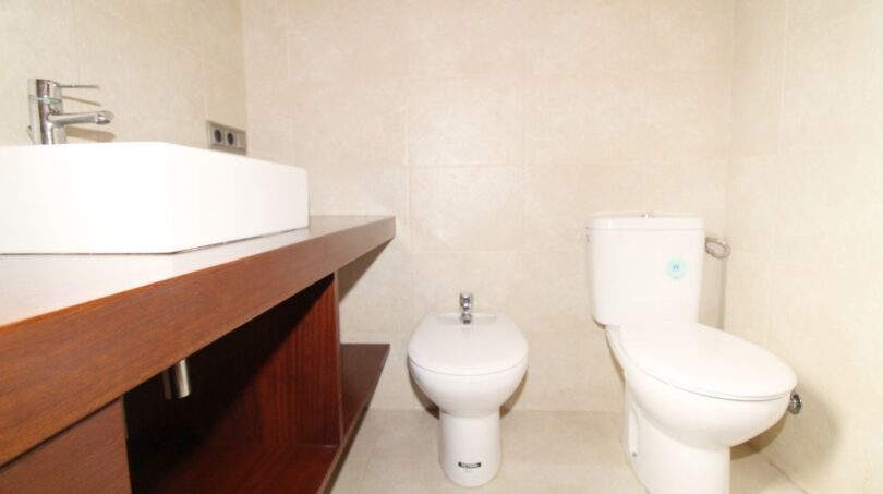 Modernes Badezimmer der Neubau-Finca mit Aufsatzwaschbecken, Bidet und WC auf hellem Fliesenboden.