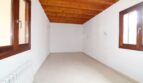 Leeres Zimmer mit Holzbalkendecke, Fliesenboden, Heizkörper und zwei Holzfenstern in Neubau-Finca Palma