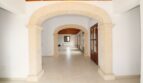 Weitläufiger Eingangsbereich mit elegantem Steinbogen, Holzdecke und weißen Wänden in Neubau-Finca, Palma