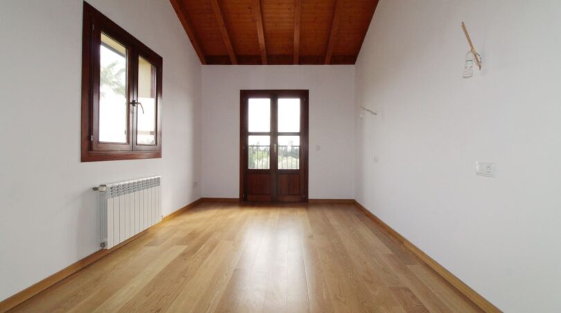 Helles Zimmer der Neubau-Finca mit Holzbalkendecke, Parkettboden und Terrassentür in Son Liebre
