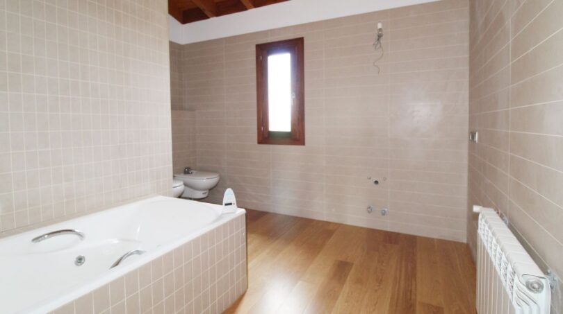 Geräumiges Badezimmer der Neubau-Finca mit Einbaubadewanne, Holzboden und Holzbalkendecke.