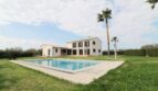 Außenansicht Neubau-Finca Son Liebre: weißes Landhaus mit Pool, Palmen und gepflegtem Rasen.
