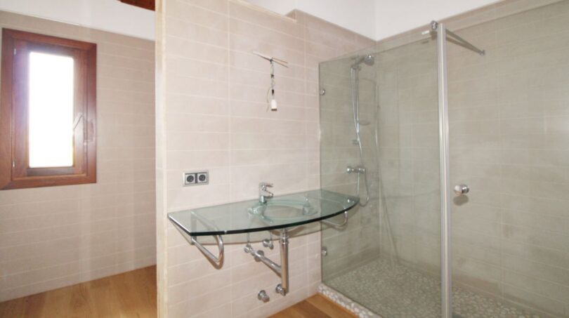 Modernes Badezimmer der Neubau-Finca mit Glaswaschbecken und ebenerdiger Dusche mit Glasabtrennung.