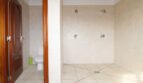 Geräumiges Badezimmer der Finca mit Doppeldusche, weißen Fliesen und separatem WC-Bereich mit Holztür.