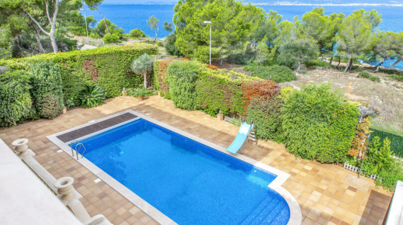 Luxusvilla Llucmajor: Privater Pool mit Meerblick, gepflegter Gartenanlage und blauem Mittelmeer im Hintergrund.