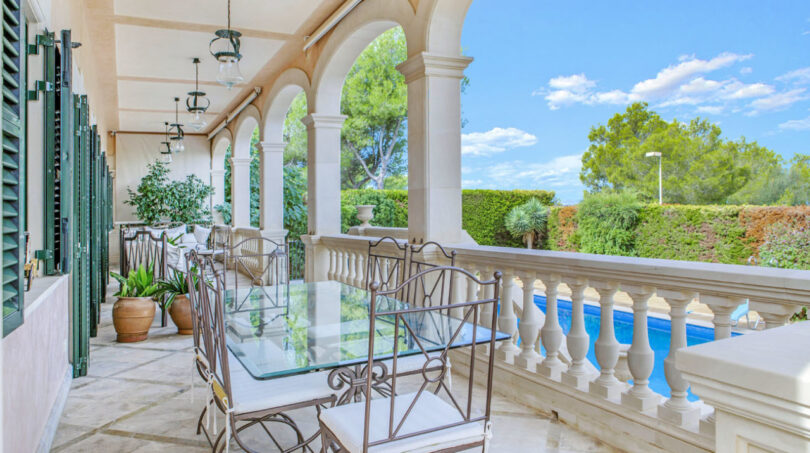 Elegante Säulenterrasse mit Schmiedeeisenmöbeln und Poolblick der Luxusvilla in Llucmajor