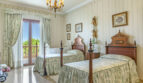 Elegantes Schlafzimmer der Luxusvilla in Llucmajor mit zwei Einzelbetten, Kronleuchter und Balkon mit Meerblick.