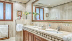 Elegante baño de mármol de la villa de lujo en Llucmajor con lavabo doble, armario de madera y espejo grande