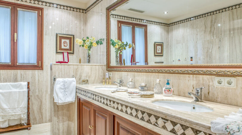 Elegante baño de mármol de la villa de lujo en Llucmajor con lavabo doble, armario de madera y espejo grande