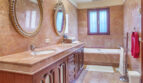 Luxuriöses Marmorbad der Meereslinie-Villa in Llucmajor mit vergoldeten Spiegeln und elegantem Holzwaschtisch