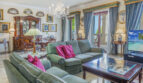 Elegantes Wohnzimmer der Luxusvilla in Llucmajor mit Kronleuchter, grünen Sofas und Meerblick.
