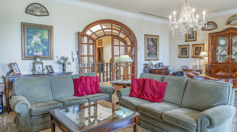 Elegantes Wohnzimmer der Luxusvilla in Llucmajor mit Kristallleuchter, Bogentür und klassischen Sofas