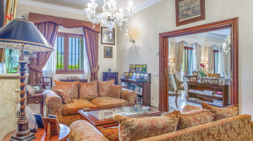 Elegantes Wohnzimmer der Luxusvilla in Llucmajor mit Kristallleuchter, Damast-Sofas und Meerblick
