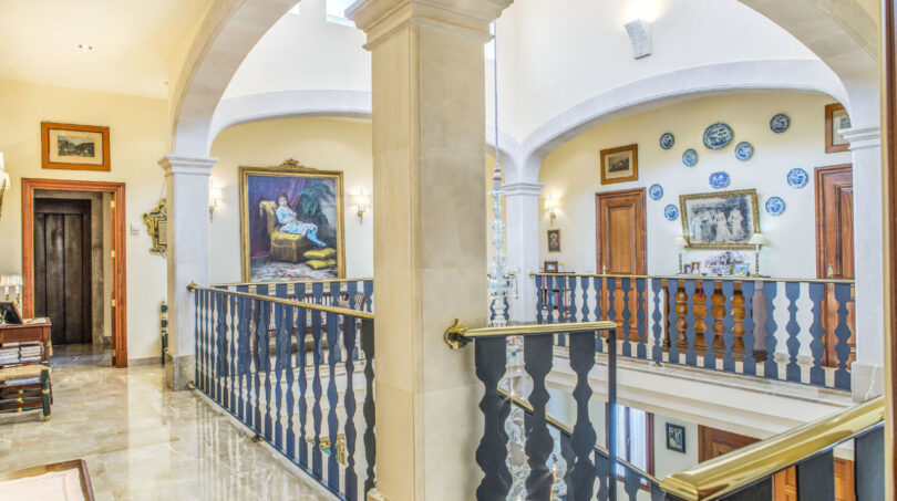 Eleganter Galerieflur mit Bogenkonstruktion, blau-weißem Geländer und Gemälden in Luxusvilla Llucmajor