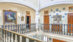 Eleganter Galerieflur der Luxusvilla in Llucmajor mit Kronleuchter, Gemälden und blau-weißem Balustergeländer.