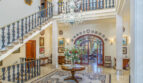 Repräsentative Einganghalle der Luxusvilla mit Kristallkronleuchter, Marmorboden und elegantem Treppenaufgang.