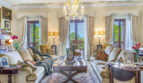 Elegante sala de estar de la villa de lujo en Llucmajor con lámpara de araña, sofás de terciopelo y vista al mar a través de altas puertas de terraza.