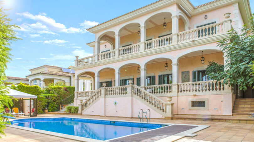 Luxusvilla in Llucmajor: Elegante Außenansicht mit Pool, Doppeltreppe und umlaufenden Balkonen.