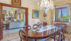 Elegantes Esszimmer der Luxusvilla in Llucmajor mit Kristallleuchter, antikem Holztisch und Blick ins Wohnzimmer.
