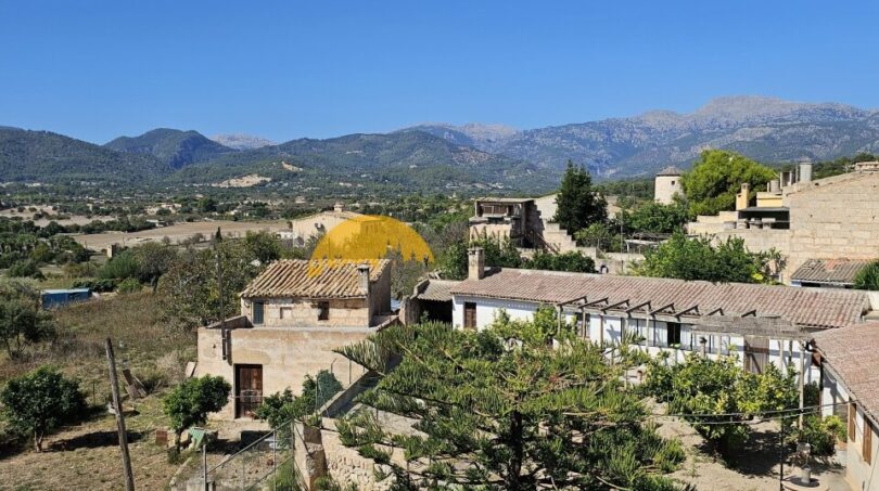 Panoramablick vom Stadthaus in Inca auf Dächer, Garten und die Tramuntana-Berge unter blauem Himmel.