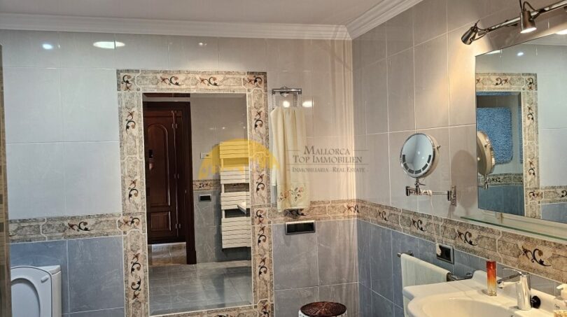 Elegantes Badezimmer im Stadthaus Inca mit Marmorfliesen, Doppelwaschbecken und dekorativem Wandspiegel.