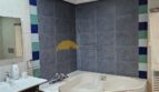 Badezimmer des Stadthauses in Inca mit Eckbadewanne, grauen Fliesen und bunten Akzenten