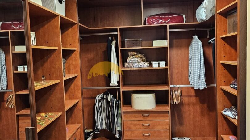 Geräumiges Ankleidezimmer mit Holzeinbauten, Schubladen und Hängestangen im Stadthaus Inca