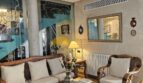Elegantes Wohnzimmer mit Rattanmöbeln, Wandspiegel und Klimaanlage im Stadthaus Inca