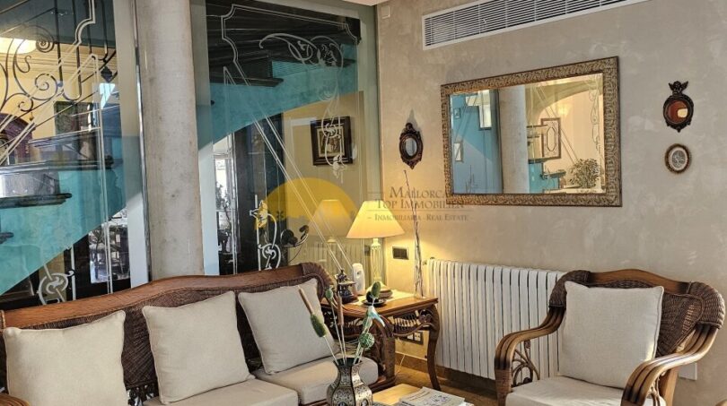 Elegantes Wohnzimmer mit Rattanmöbeln, Wandspiegel und Klimaanlage im Stadthaus Inca