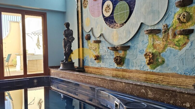 Innenpool mit Kunstwand, klassischer Statue und Mosaikelementen im Stadthaus Inca