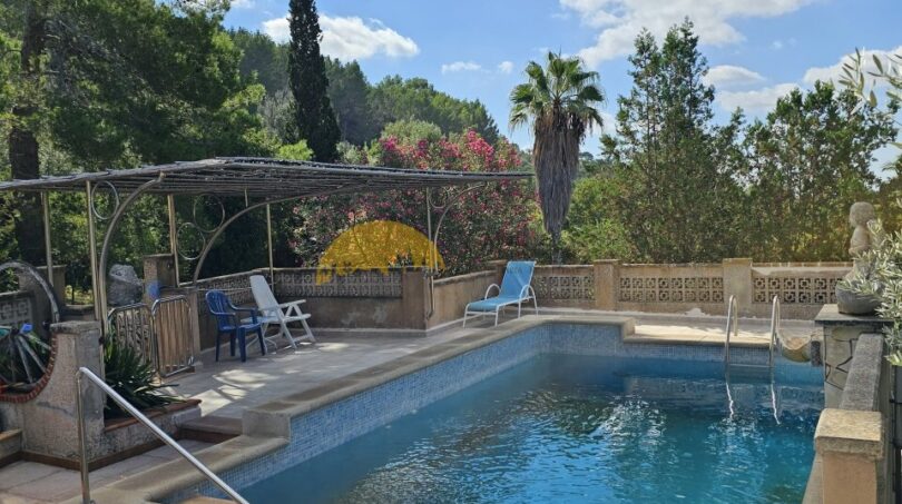 Außenpool der Finca bei Inca mit Pergola, Liegestühlen und üppigem mediterranem Garten mit Palmen.