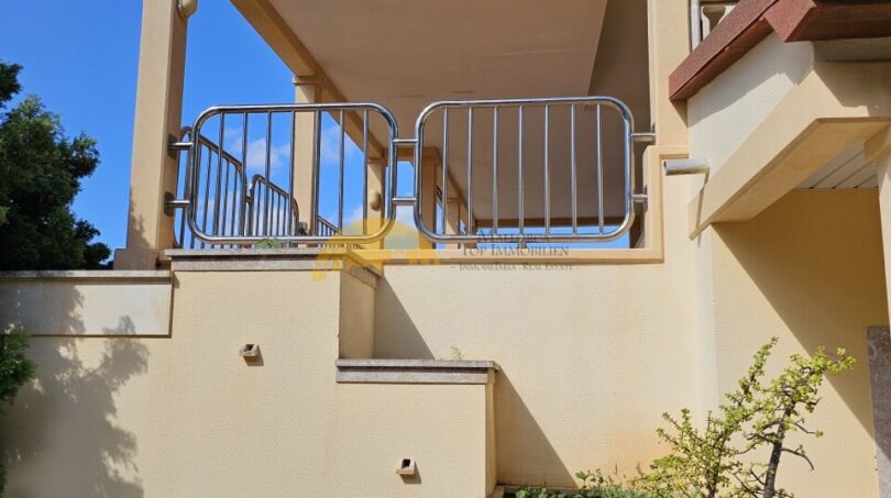 Überdachter Balkon mit Edelstahlgeländer am Finca-Anwesen bei Inca, umgeben von mediterranen Pflanzen.
