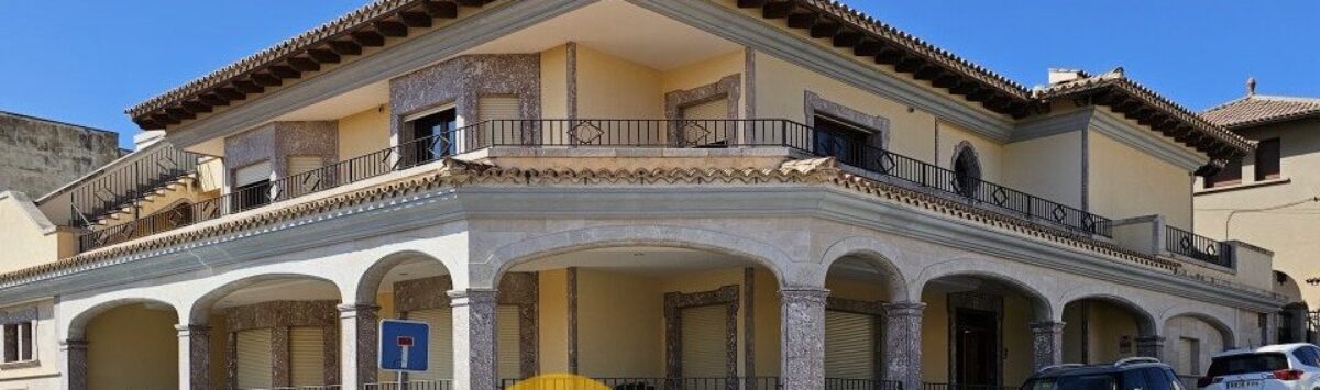 Exterior view of a two-story townhouse in Inca with arcades, balconies and Mediterranean architecture.