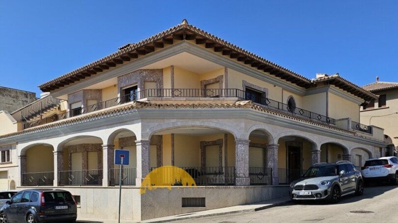 Exterior view of a two-story townhouse in Inca with arcades, balconies and Mediterranean architecture.