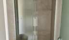 Modernes Duschbad mit Glasschiebtür, Regendusche und eleganten Natursteinwandfliesen in Luxuswohnung Palma.
