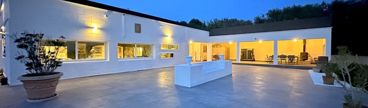 Weitläufige Außenterrasse mit Natursteinboden einer modernen weißen Villa in Marratxí bei Abenddämmerung