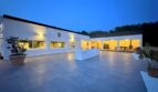 Weitläufige Außenterrasse mit Natursteinboden einer modernen weißen Villa in Marratxí bei Abenddämmerung