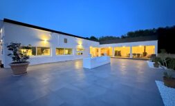 Amplia terraza exterior con suelo de piedra natural de una villa blanca moderna en Marratxí al atardecer