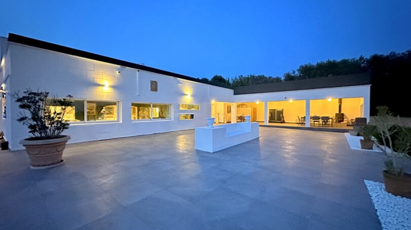 Weitläufige Außenterrasse mit Natursteinboden einer modernen weißen Villa in Marratxí bei Abenddämmerung