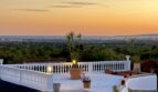 Weitläufige Dachterrasse mit weißem Baluster, Palmen und Panoramablick über Marratxí bis zum Meer bei Sonnenuntergang.