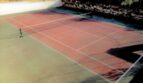 Roter Tennisplatz mit Netz, Steinmauer und Bäumen der Luxusvilla in Marratxí