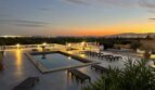 Beleuchteter Pool mit Panoramablick auf Marratxí bei Sonnenuntergang, umgeben von eleganten Liegestühlen.