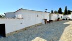Außenansicht einer weißen mediterranen Villa in Marratxí mit Natursteinpflaster und rotem Ziegeldach.