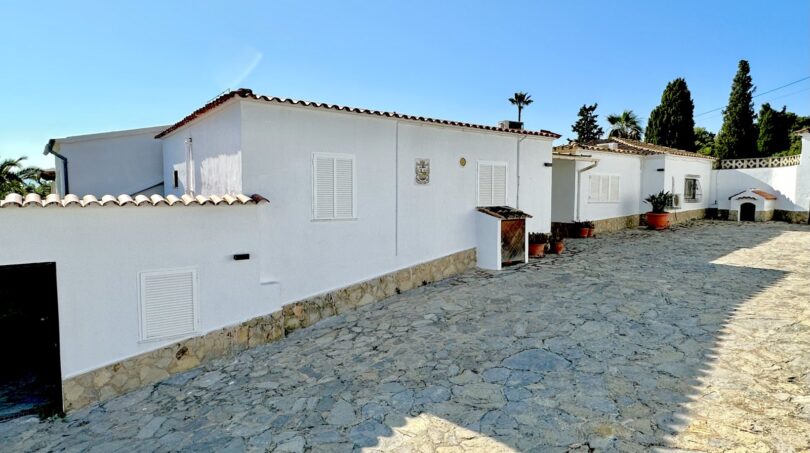Außenansicht einer weißen mediterranen Villa in Marratxí mit Natursteinpflaster und rotem Ziegeldach.
